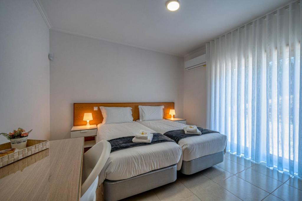 a white bedroom with a large bed with white sheets at Central Suítes Arouca in Arouca