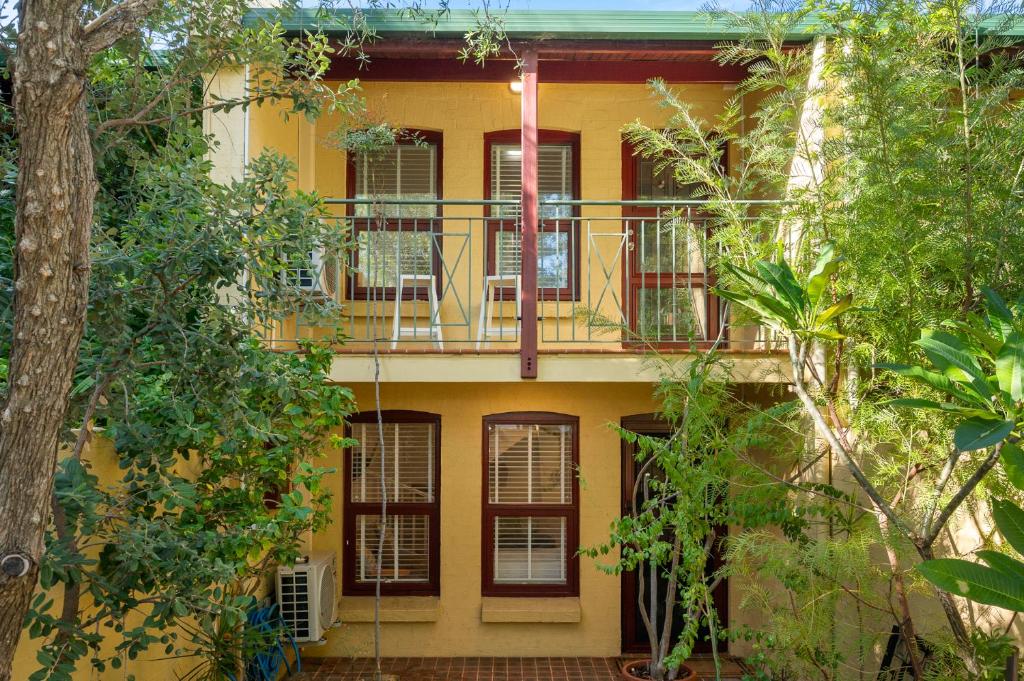 a yellow building with a balcony and trees at Central Freo Hideaway in Fremantle