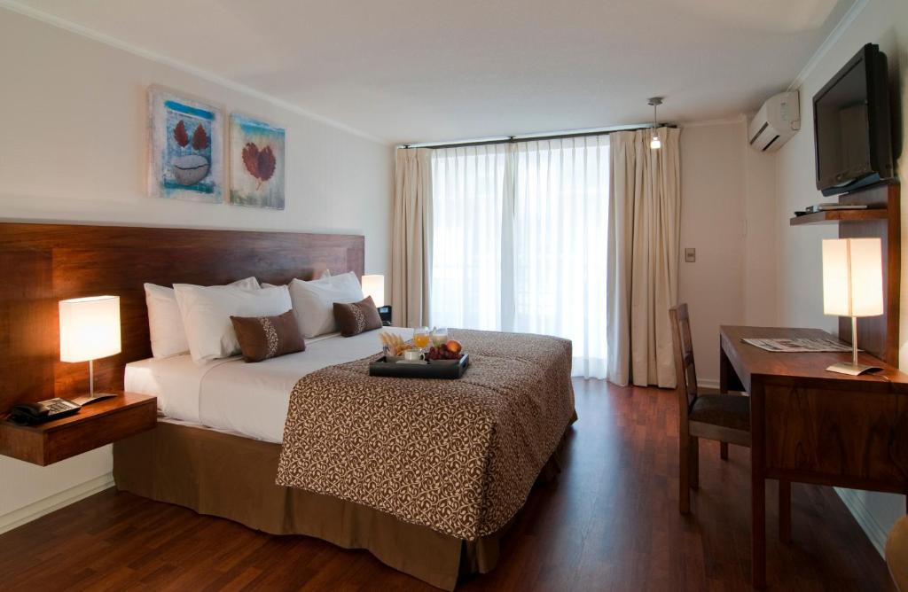 a bedroom with a bed with a desk and a television at Park Plaza Apart Hotel in Santiago