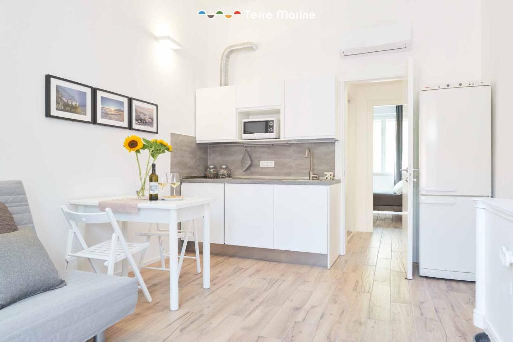 a kitchen with white cabinets and a table and a dining room at Urban Chic, Terre Marine in La Spezia