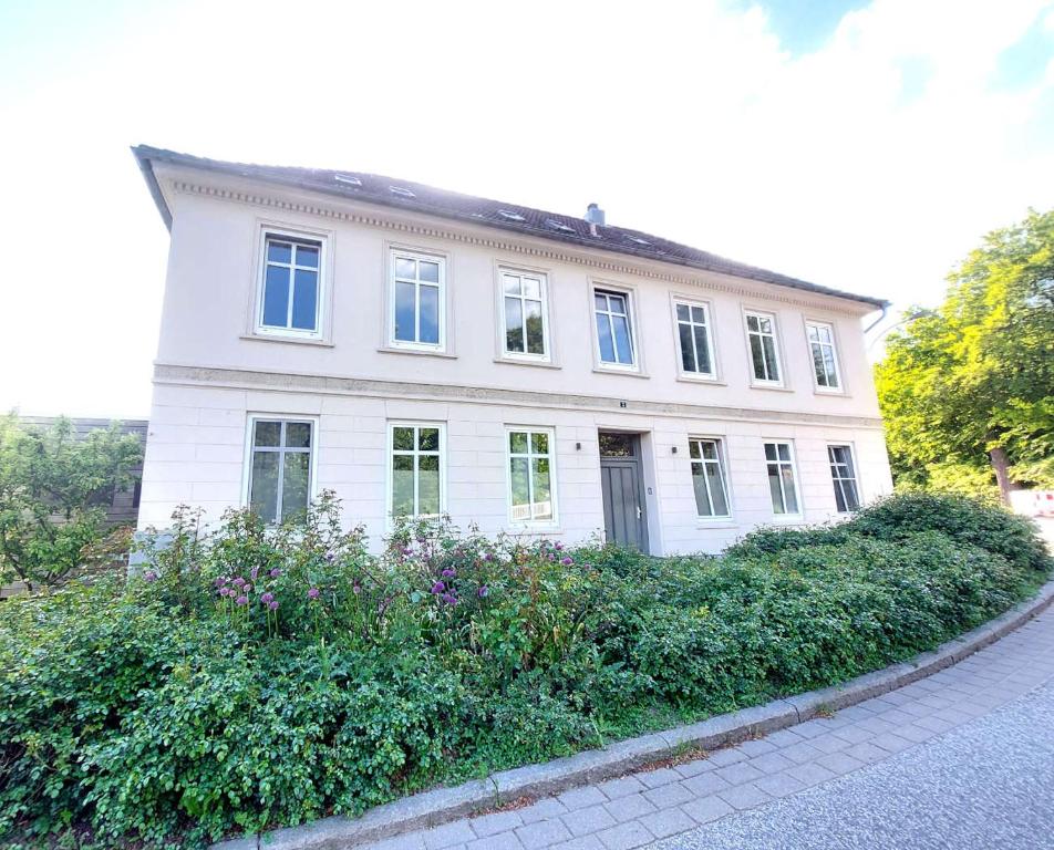 a white house with windows and bushes in front of it at Historisches Stadthaus Schwentine in Eutin