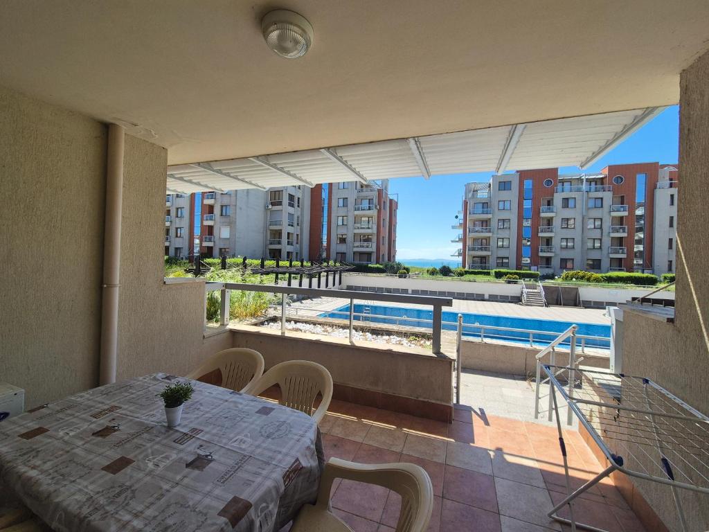 a balcony with a table and a swimming pool at Helios Beach Apart Garden in Pomorie