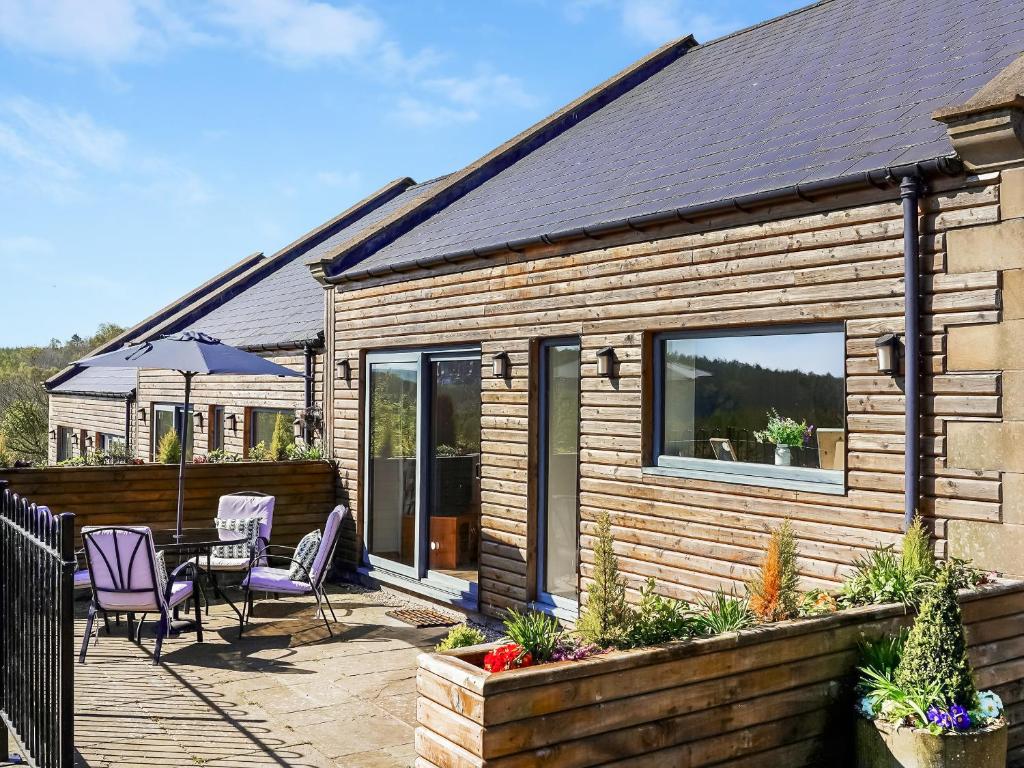 a wooden house with chairs and a table on a patio at One The Old Stables in Knitsley