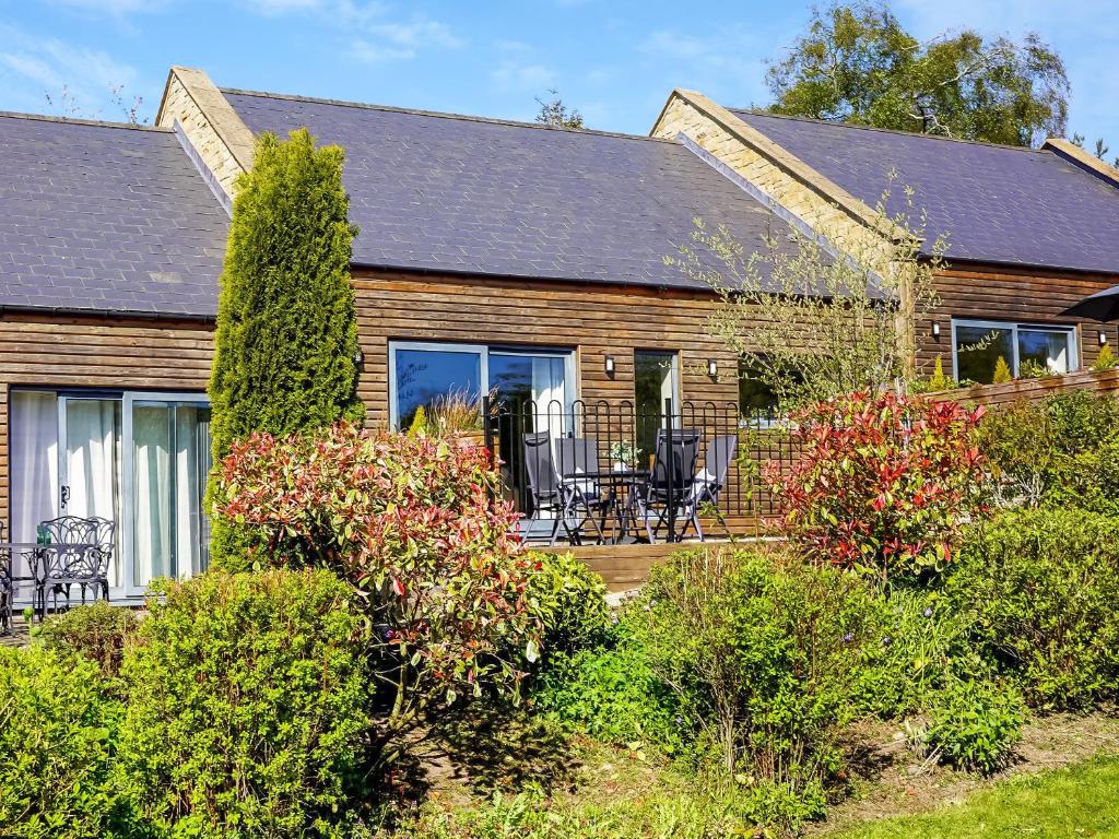 a wooden house with a deck and patio at Two The Old Stables in Knitsley