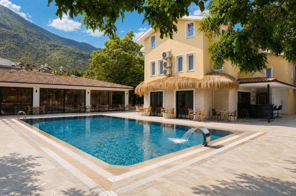a swimming pool in front of a building with a house at Güneş Boutique Hotel - Oludeniz in Oludeniz