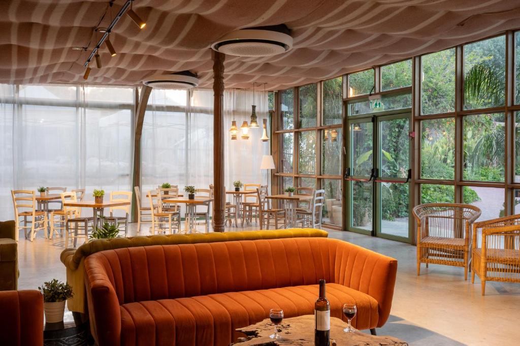 a living room with a couch and tables and windows at Almog Hotel in Almog