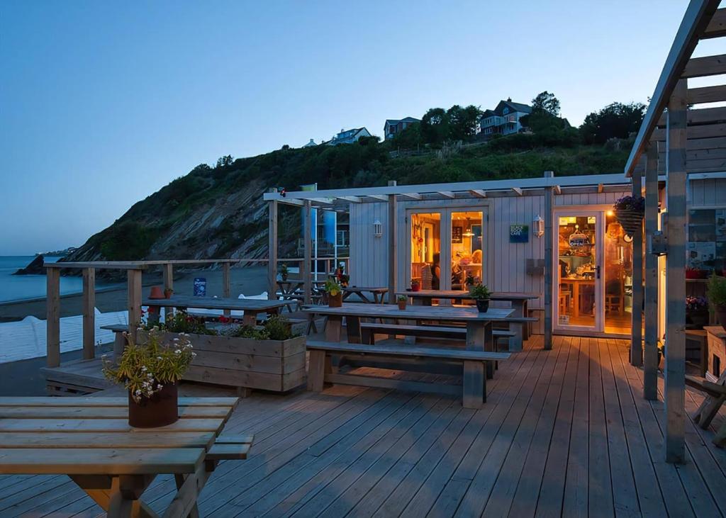 a deck with a house with tables and benches at Millendreath Beach Resort in Looe