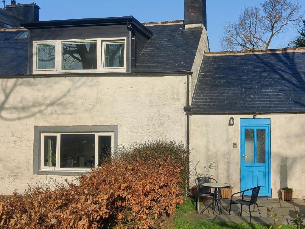 a white house with a blue door and a table at Cowar Bothy in Dalbeattie