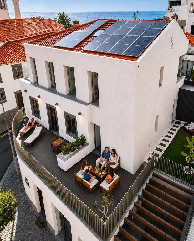 a group of people sitting on the roof of a house with solar panels at Heritage Apartments in Câmara de Lobos