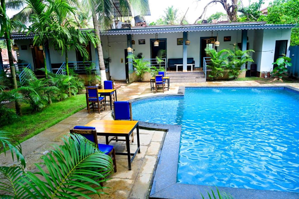 a pool with tables and chairs next to a house at Sarovar Morjim in Morjim