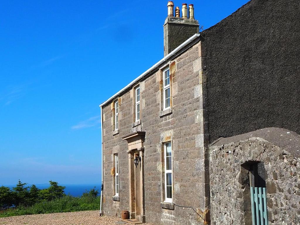 an old stone building with a chimney on top of it at Ballygroggan Farmhouse - Uk35208 in Machrihanish