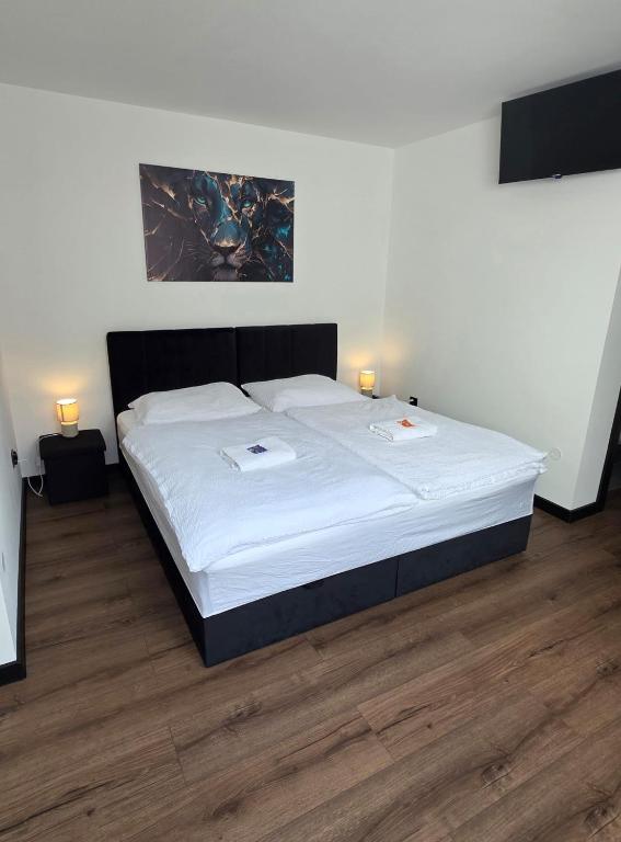 a bedroom with a bed with white sheets and two lamps at RG Apartments in Šamorín