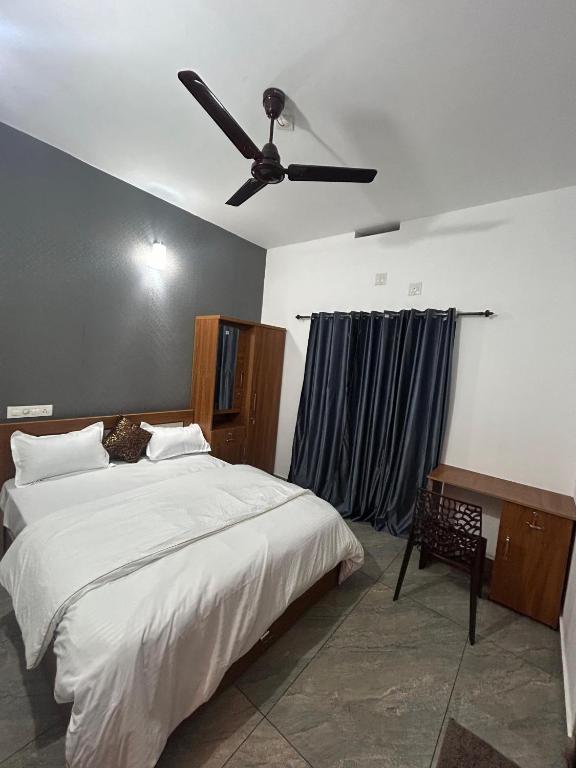 a bedroom with a bed with a ceiling fan at nas villa in Kalpetta