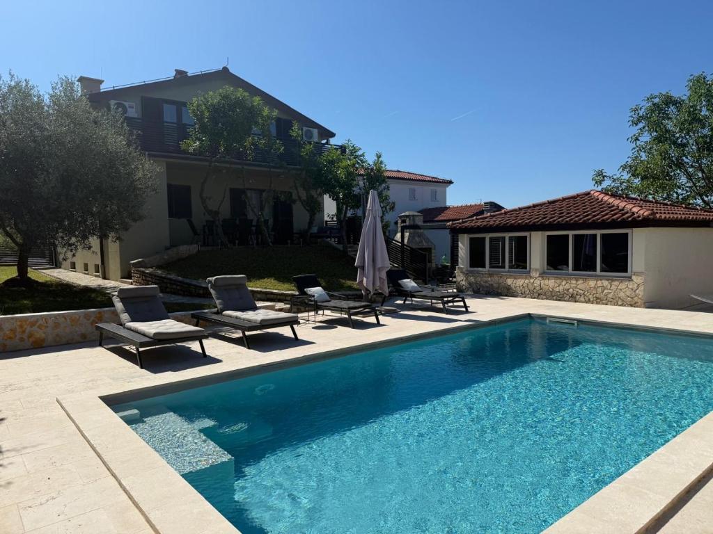 a swimming pool with two chairs and a house at Ferienhaus Marija mit Pool in Vilanija