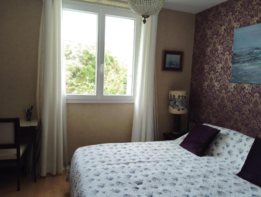 a bedroom with a bed and a large window at Kerlir in Ploemeur