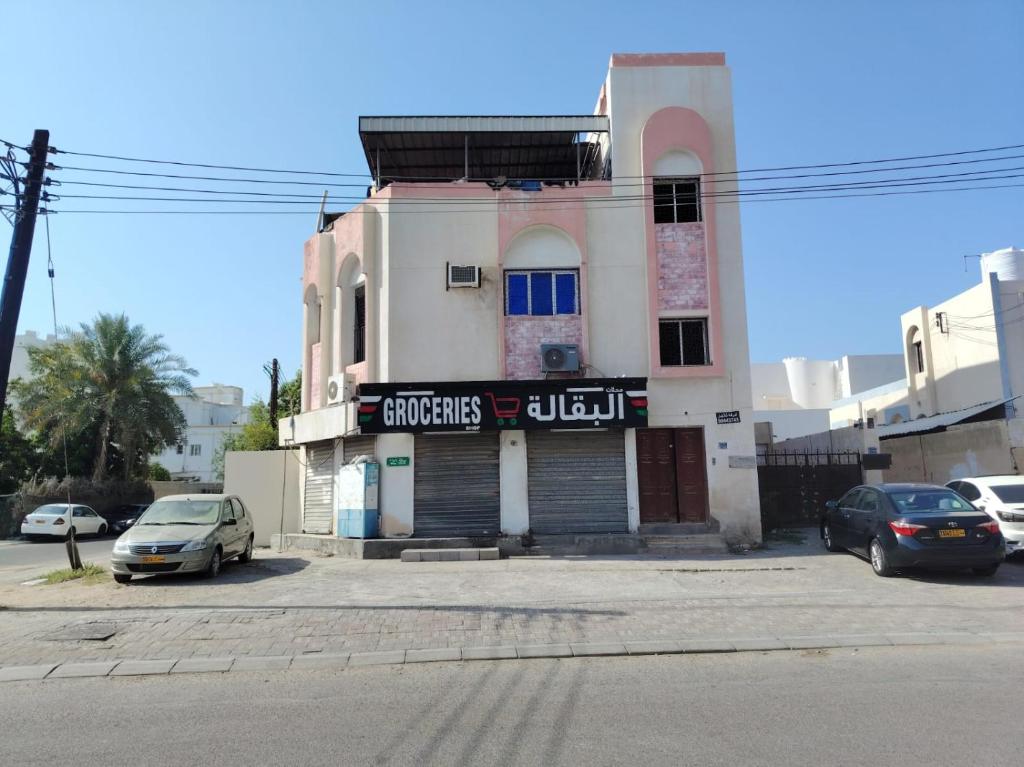 a building with cars parked in a parking lot at Turkish beach hostel in Muscat
