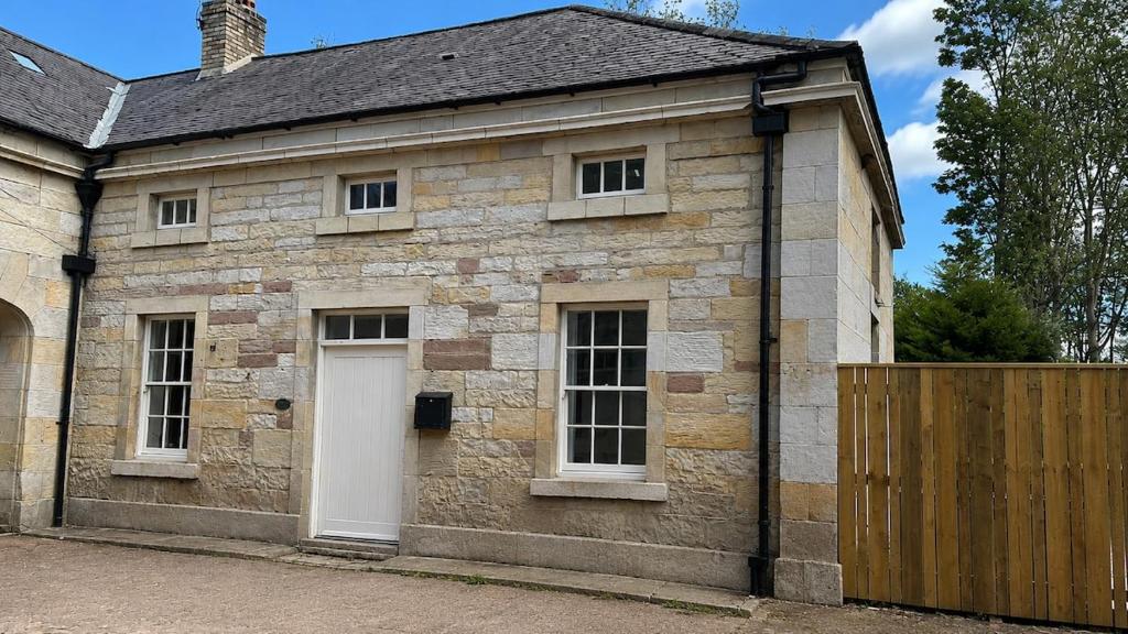 an old stone house with a white door and a gate at Farrier's Rest in Belford
