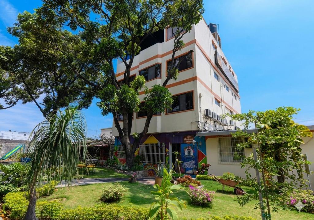 a building with a tree in front of it at Hotel de Alborada - Cerca Del Aeropuerto in Guayaquil