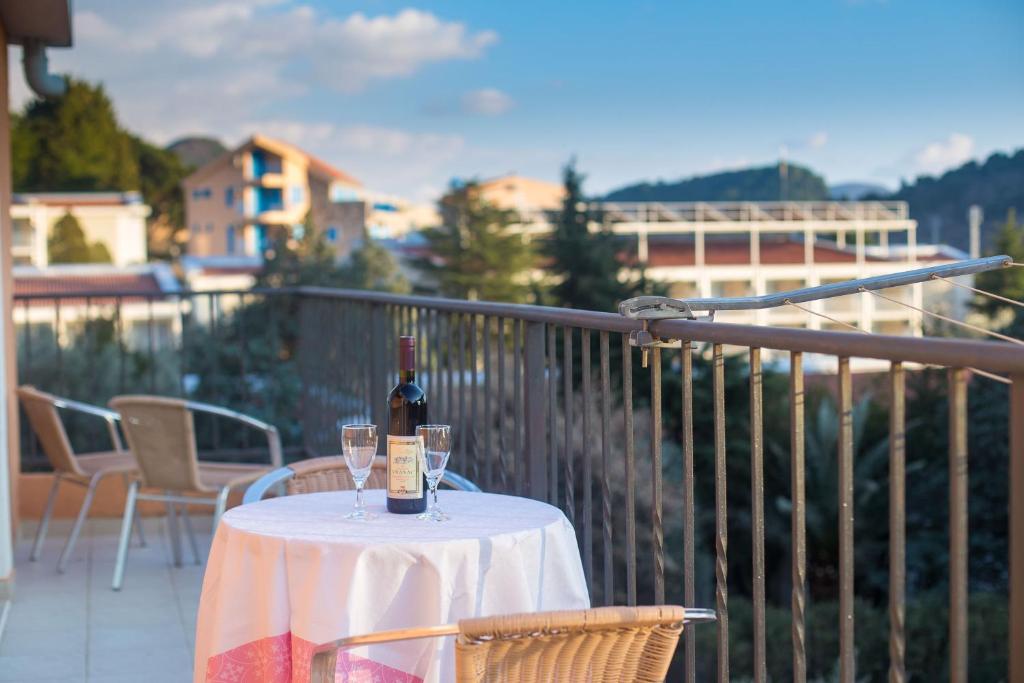een tafel met een fles wijn en twee glazen op een balkon bij Villa Nadezda in Petrovac na Moru
