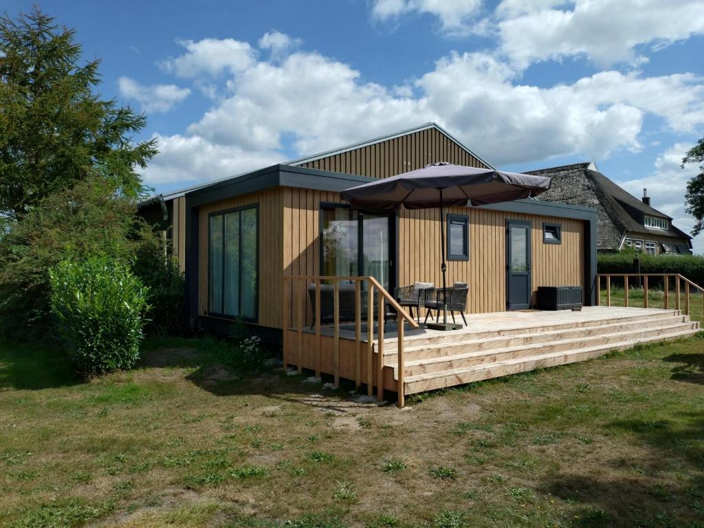 a small house with a deck with an umbrella at OV815- Chalet Eveline in Blokzijl