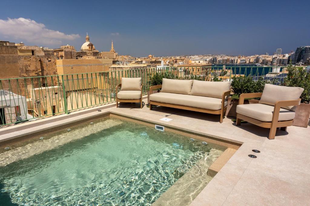 a swimming pool with two chairs and a view of the city at The Vincent Boutique Hotel, BW Premier Collection in Valletta