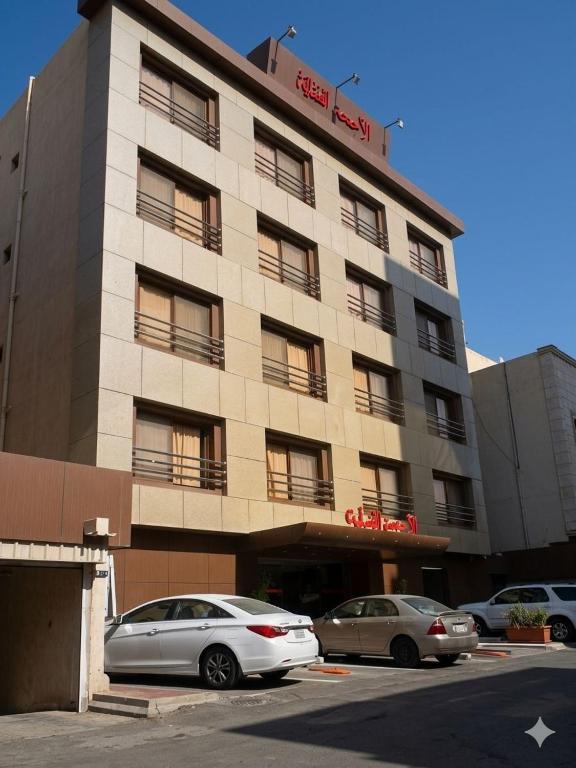 two cars parked in front of a building at الا جنحة المخملية للشقق المخدومة - السلامة in Jeddah