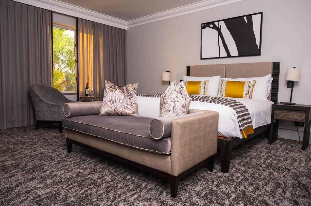 a bedroom with a bed and a couch and a chair at Golden Horse Hotel in Pietermaritzburg