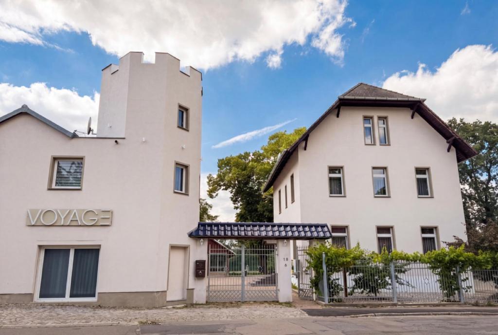 a white building with a fence next to it at Voyage Pension in Leipzig