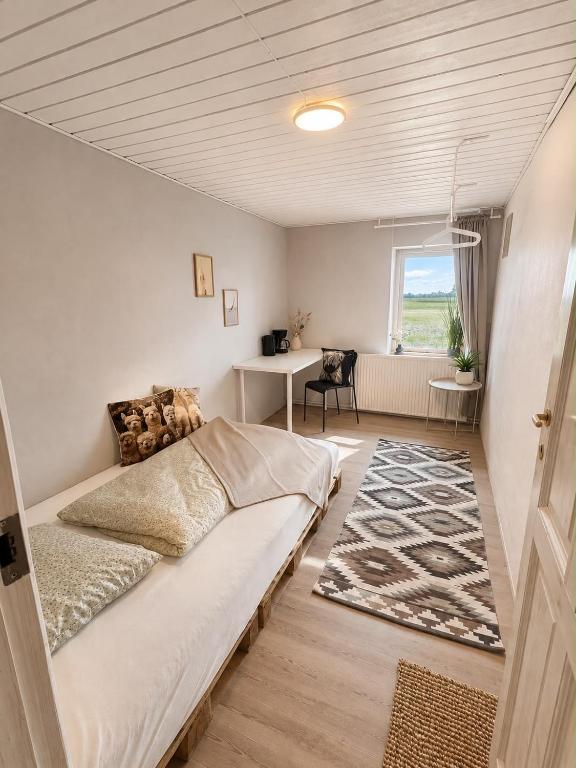 a bedroom with a bed and a desk and a window at Alpaca Bed & Fields in Snedsted