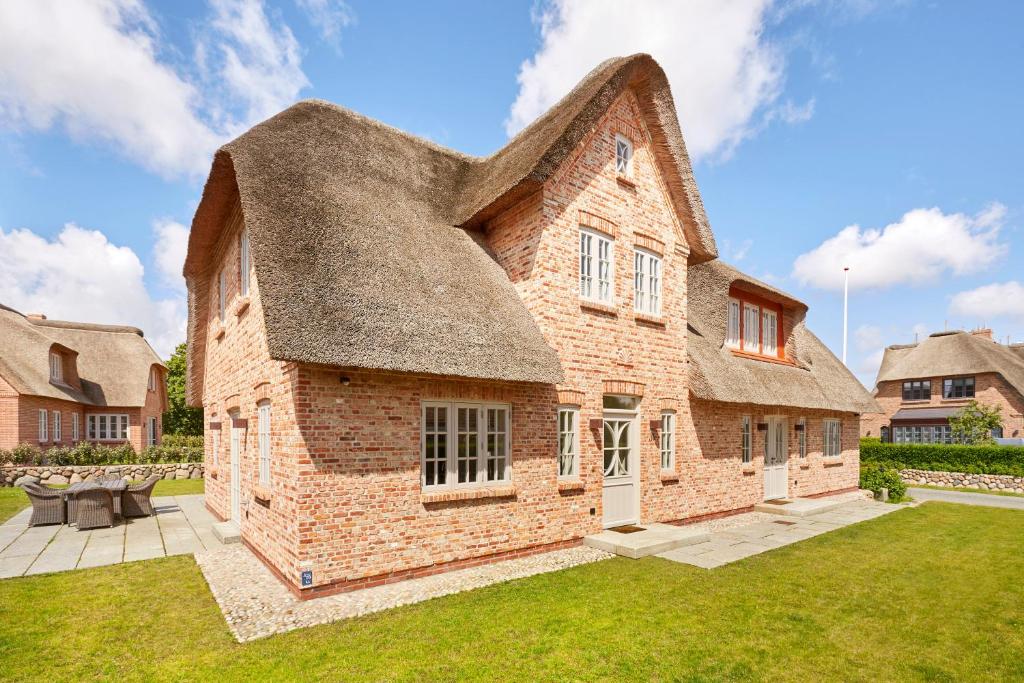a large brick building with a thatched roof at Wiesen Engel in Oldsum