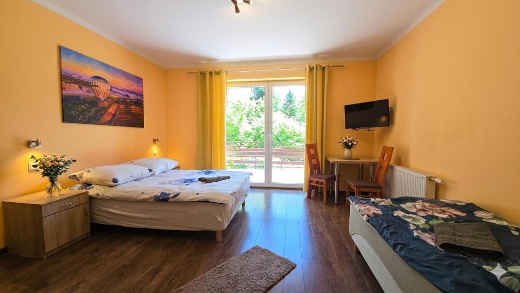 a bedroom with two beds and a tv and a window at Stokrotka noclegi Nałęczów in Nałęczów