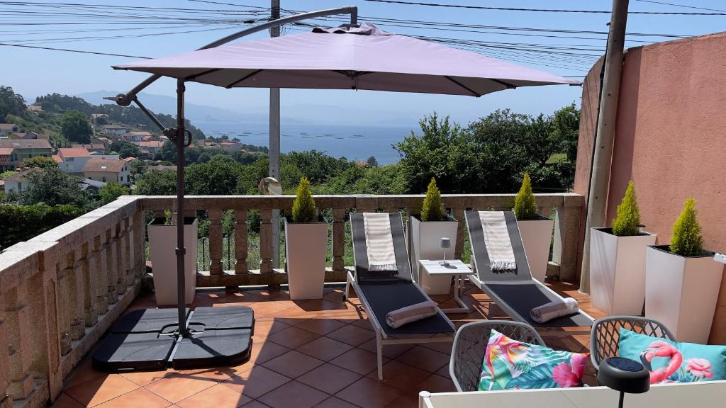 a patio with chairs and an umbrella on a balcony at Jo's Studio Flat Limens in Cangas de Morrazo