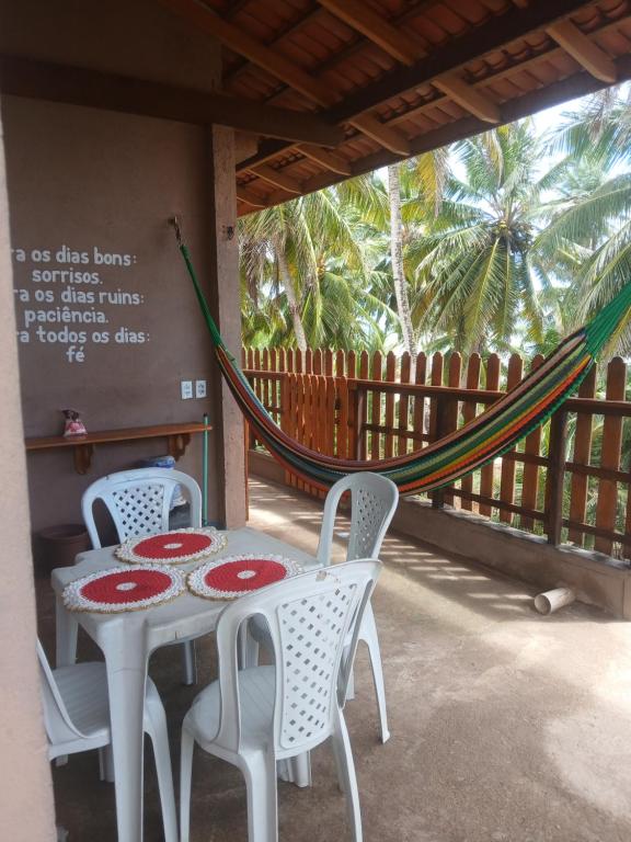 a table and chairs on a porch with a hammock at Casa pénareia in Amontada