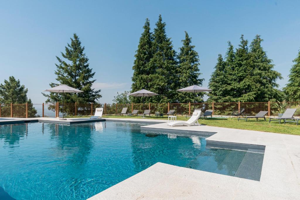 a large swimming pool with chairs and umbrellas at TerraSena Mountain Village - Serra da Estrela in Seia