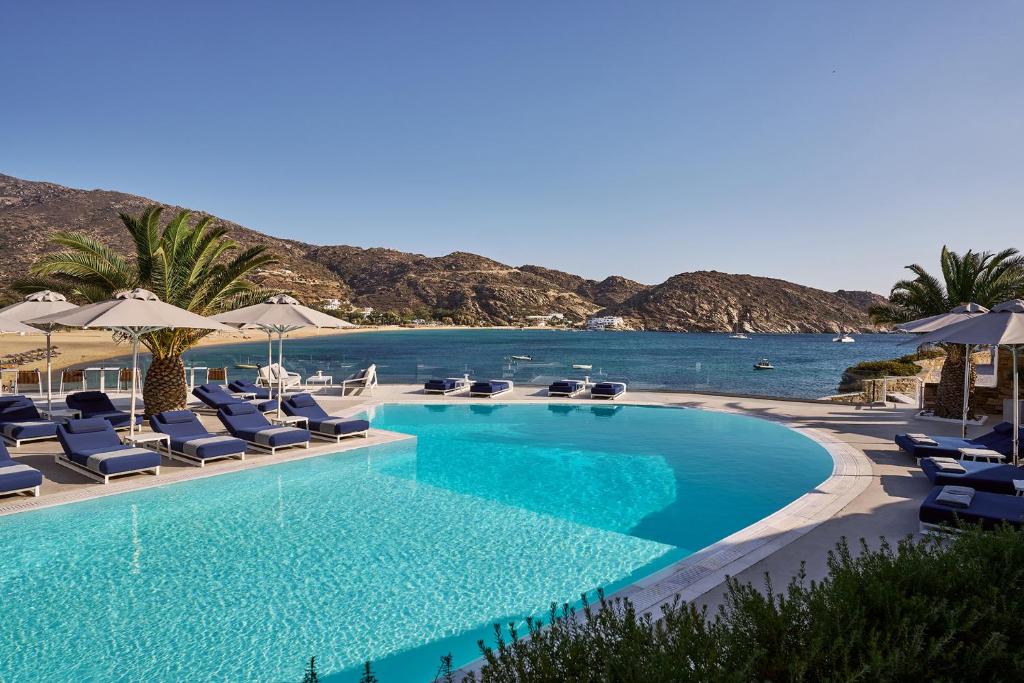 a swimming pool with lounge chairs and the ocean at Ios Palace Hotel & Spa in Mylopotas