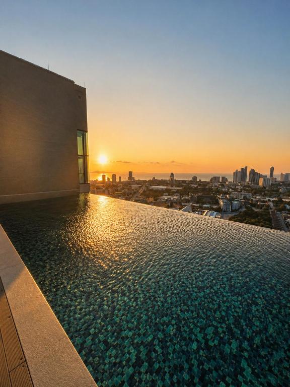a swimming pool on top of a building with a sunset at Infinity Pool at Pattaya Posh in North Pattaya
