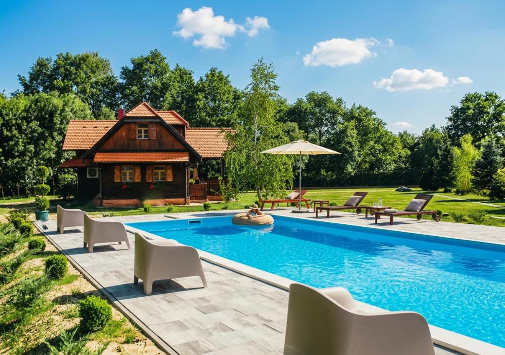 a pool with chairs and a house in the background at Moslavačka Priča Holiday Homes in Mala Ludina