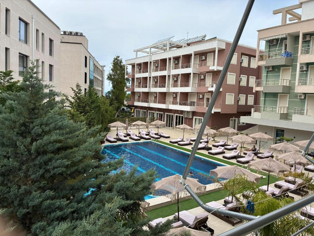 a swimming pool with chairs and umbrellas in a hotel at Radhima Sun Studio in Vlorë