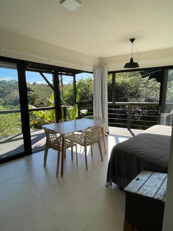 a bedroom with a table and chairs and a large window at Casa Fluila in Praia do Rosa