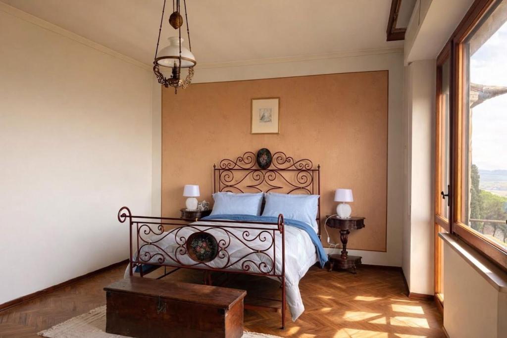 a bedroom with a bed with blue pillows and a window at La Terrazza sul Lago in Panicale