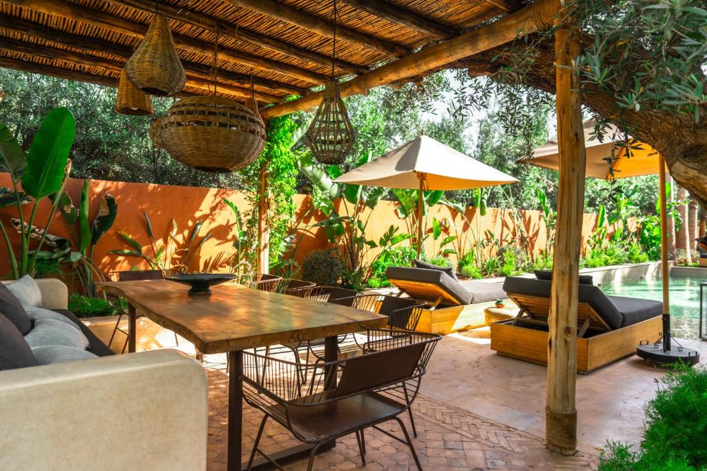 a patio with a table and chairs and an umbrella at Villa Madjha Ecolodge Marrakech in Marrakesh