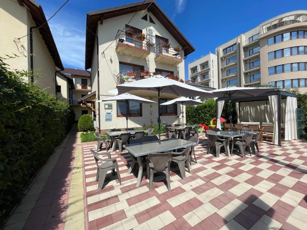 an outdoor patio with tables and chairs and umbrellas at Pensiunea Orion in Costinesti