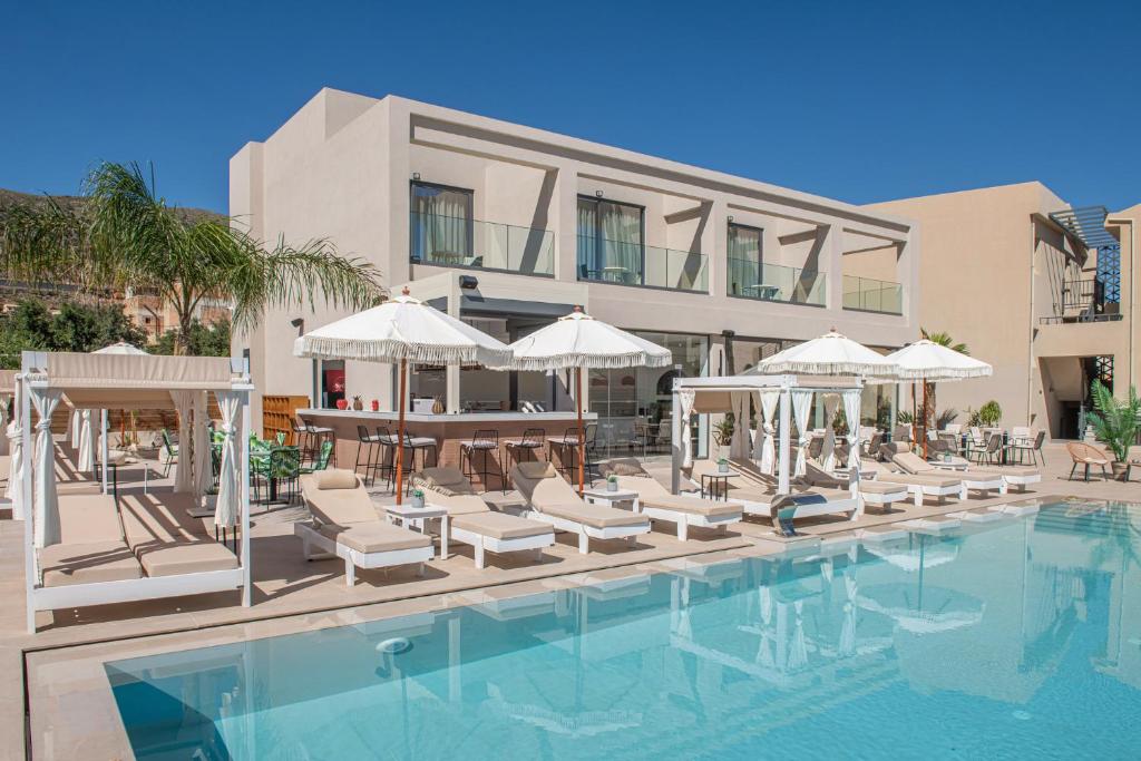 a hotel with a swimming pool with chairs and umbrellas at Meramaglia Hotel in Malia