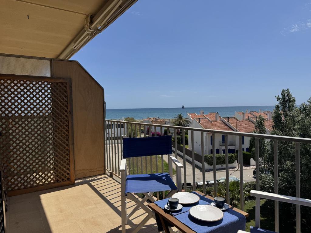 a balcony with a table and a blue chair and the ocean at Mare Nostrum 143 in Torroella de Montgrí