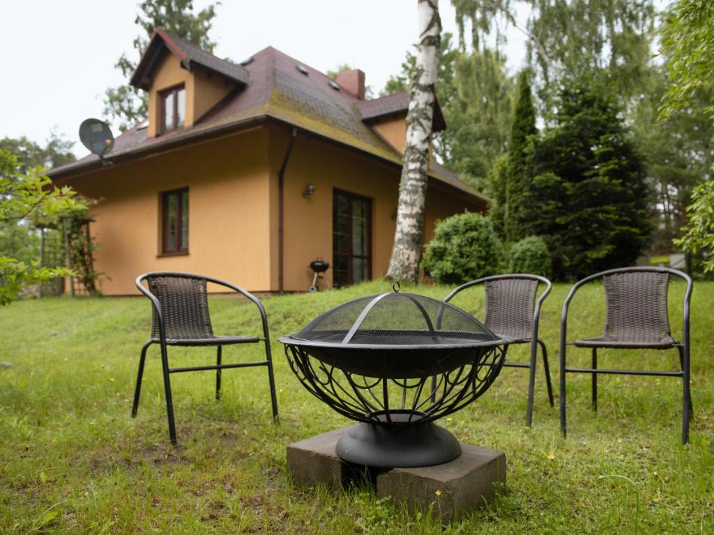 three chairs and a table in front of a house at Holiday Home Borowikowa by Interhome in Sasino