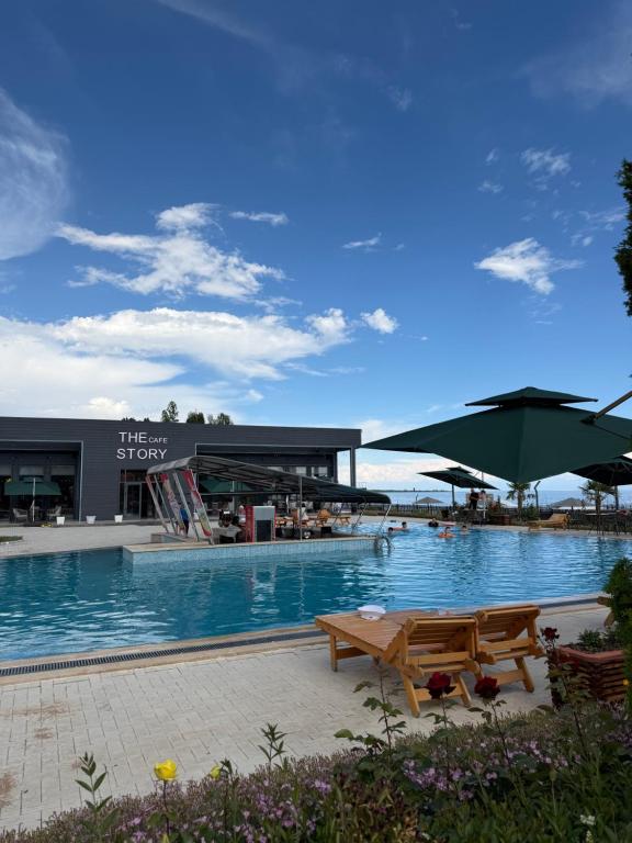 a swimming pool with two picnic tables in front of a building at Novel Hotel&Apartaments in Korumdy