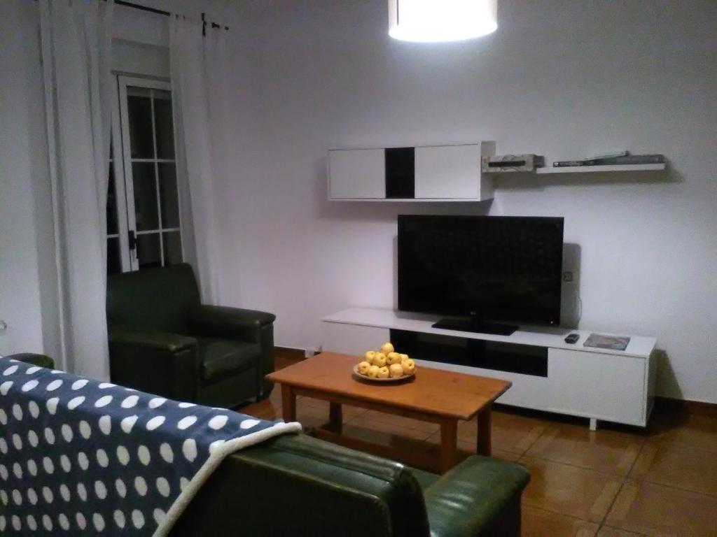ein Wohnzimmer mit einem TV und einem Couchtisch in der Unterkunft Casa Rural La Esmeralda in Navarredonda de Gredos