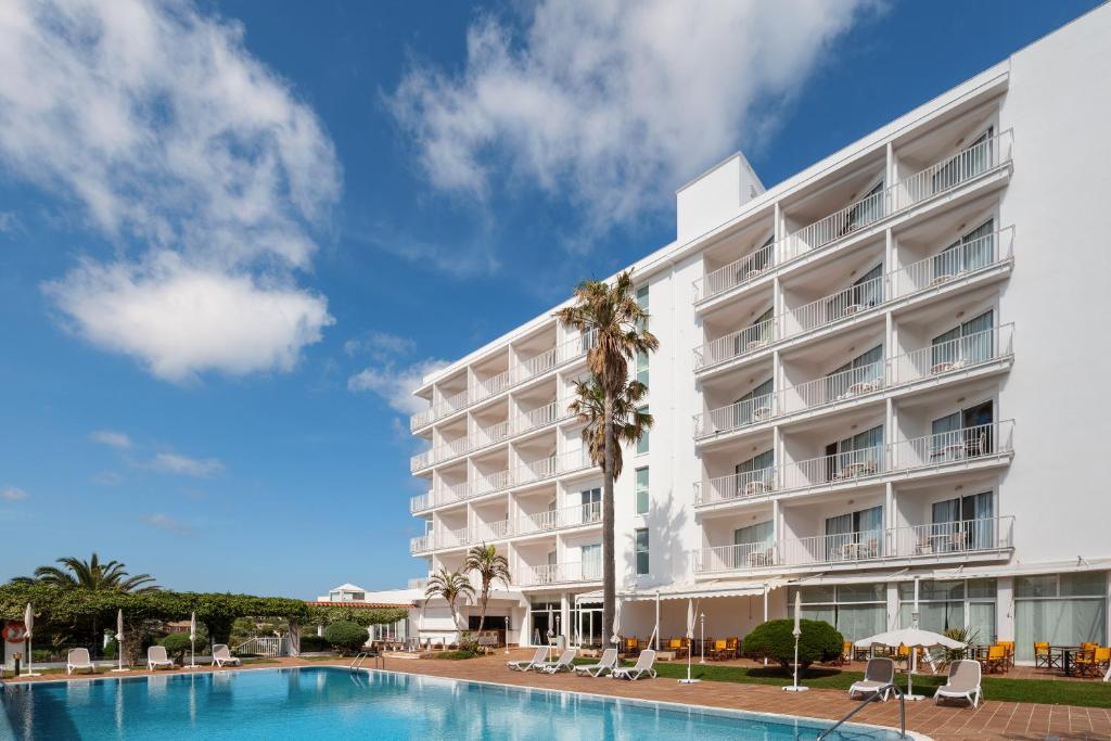 a hotel with a swimming pool in front of a building at Hotel Agamenón in Es Castell