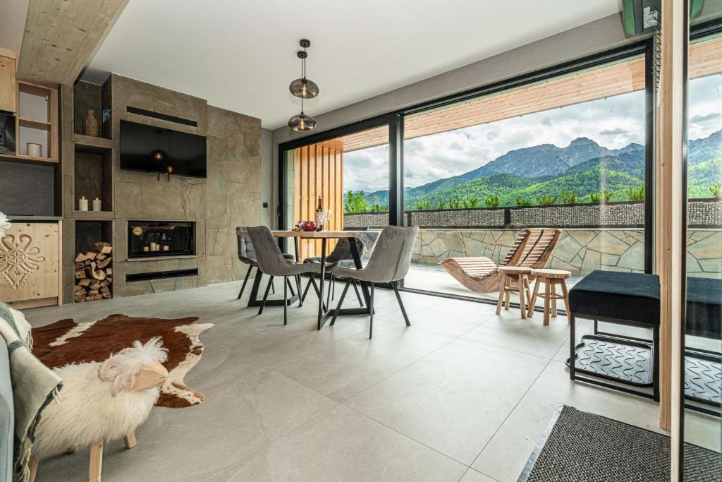 a living room with a fireplace and a table and chairs at Apartamenty Premium VIEW JACUZZI & SAUNA in Kościelisko