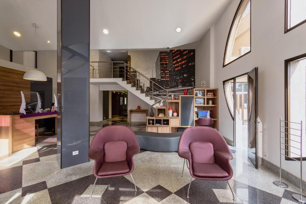 a living room with purple chairs and a staircase at Paulista Suítes by Charlie in São Paulo